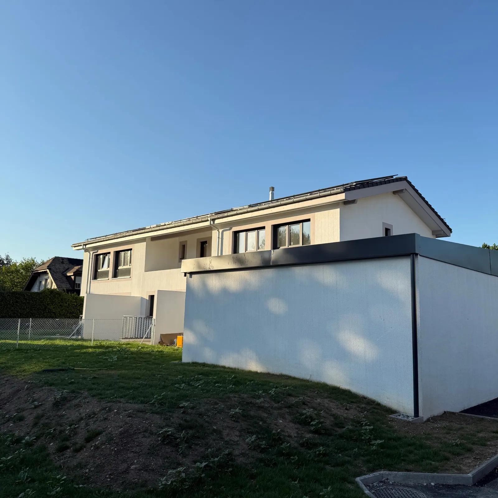 Cara 50 : maison à toiture en pente et volume annexe à toit plat sur un terrain en talus