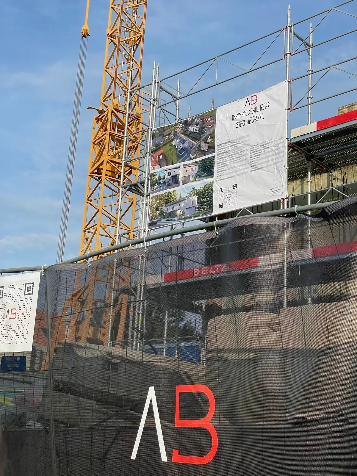 Échafaudage et grue sur un chantier, avec le panneau d'AB Immobilier Général SA